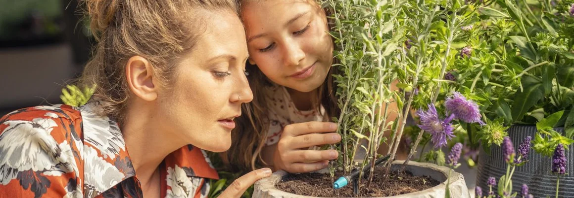 Zwei Personen betrachten ein Bewässerungssystem in einem Blumentopf.